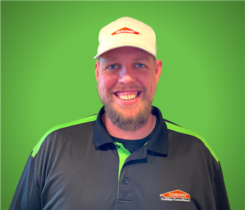 A male SERVPRO employee smiles in front of a green background.